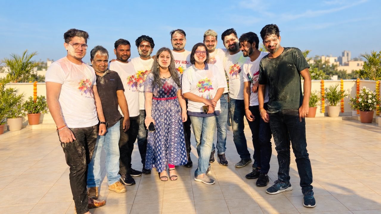 Colleagues in Holi T-shirts covered in colour on a sunny rooftop.